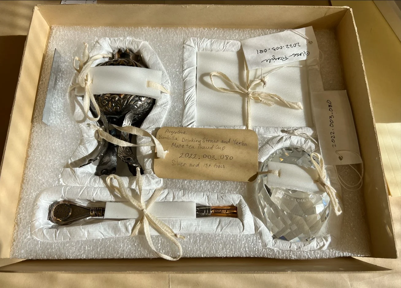 Box made of paper and styrofoam base to hold a mixture of glass and metal objects.
